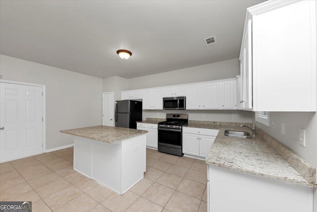 kitchen with appliances with stainless steel finishes, sink, white cabinets, light tile patterned flooring, and a center island