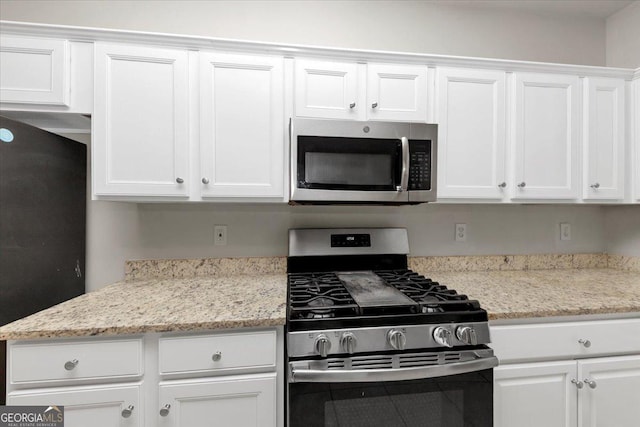 kitchen featuring white cabinets, stainless steel appliances, and light stone counters