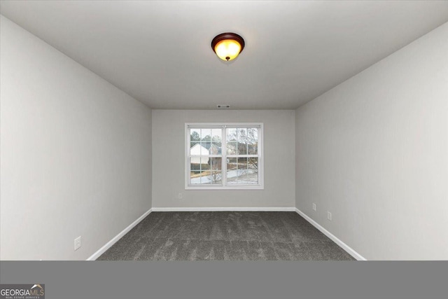 spare room featuring dark colored carpet