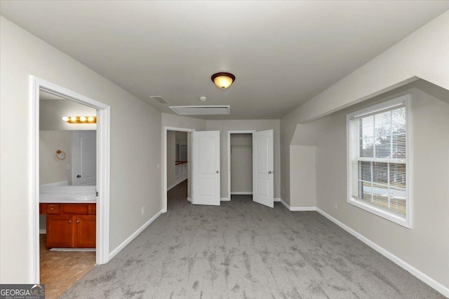 unfurnished bedroom featuring a closet, connected bathroom, and light carpet