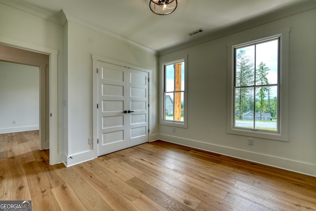 interior space with visible vents, ornamental molding, baseboards, and light wood-style flooring