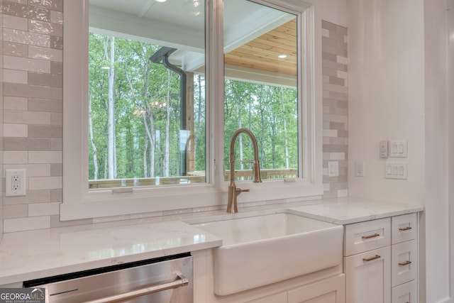 kitchen with a sink, stainless steel dishwasher, white cabinetry, and light stone countertops