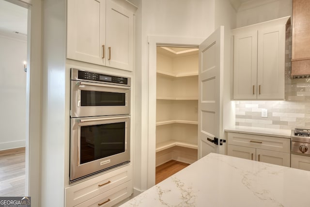 kitchen featuring decorative backsplash, appliances with stainless steel finishes, ornamental molding, and light wood finished floors
