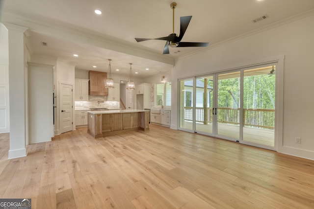 unfurnished living room featuring crown molding, ceiling fan with notable chandelier, visible vents, and light wood-type flooring