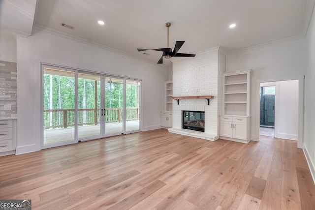 unfurnished living room with crown molding, ceiling fan, light wood finished floors, a fireplace, and visible vents