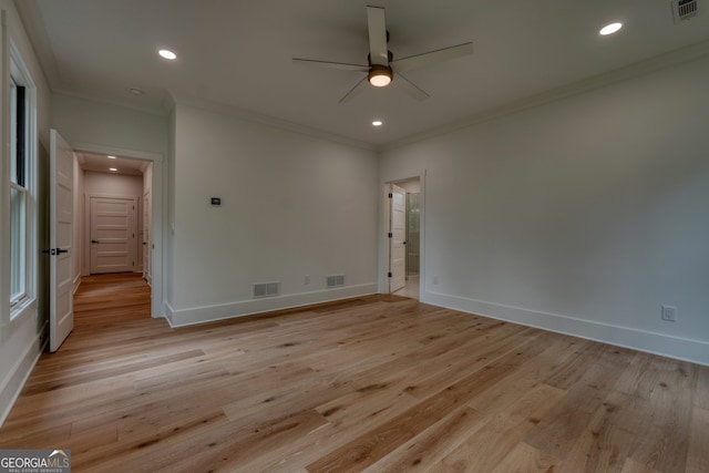 spare room featuring crown molding, ceiling fan, visible vents, and light wood-style floors