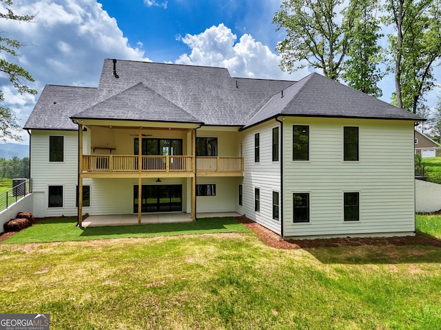 rear view of house with a shingled roof, ceiling fan, a patio area, a balcony, and a yard