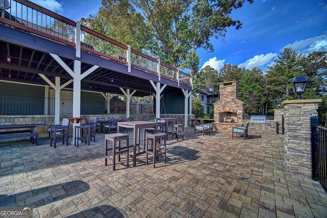 view of patio / terrace featuring an outdoor stone fireplace and a wooden deck