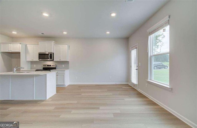 kitchen with white cabinets, appliances with stainless steel finishes, sink, and light wood-type flooring