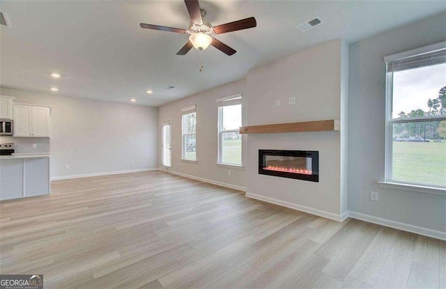 unfurnished living room featuring a healthy amount of sunlight, light hardwood / wood-style flooring, and ceiling fan