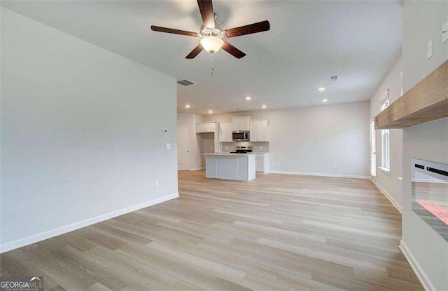 unfurnished living room with ceiling fan and light wood-type flooring