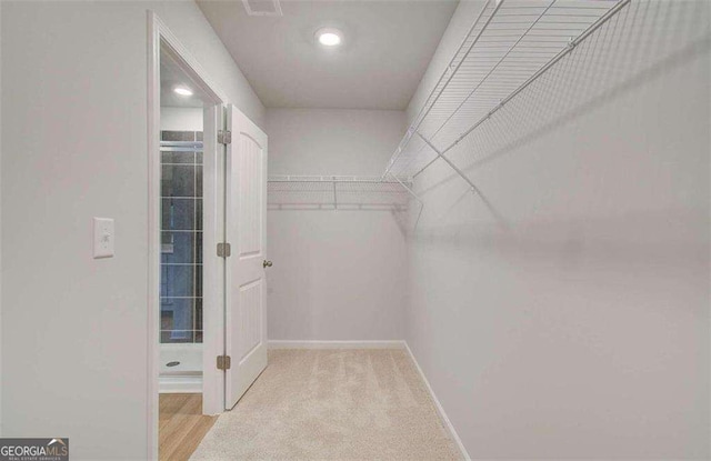 walk in closet featuring light colored carpet