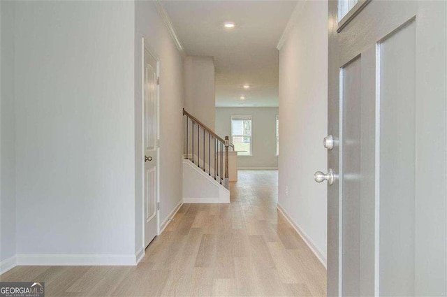 hallway featuring ornamental molding and light hardwood / wood-style floors