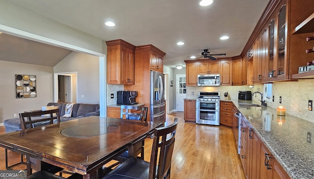 kitchen featuring appliances with stainless steel finishes, tasteful backsplash, sink, light stone counters, and light hardwood / wood-style flooring