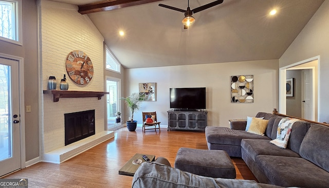 living room featuring beamed ceiling, a brick fireplace, high vaulted ceiling, and light hardwood / wood-style flooring