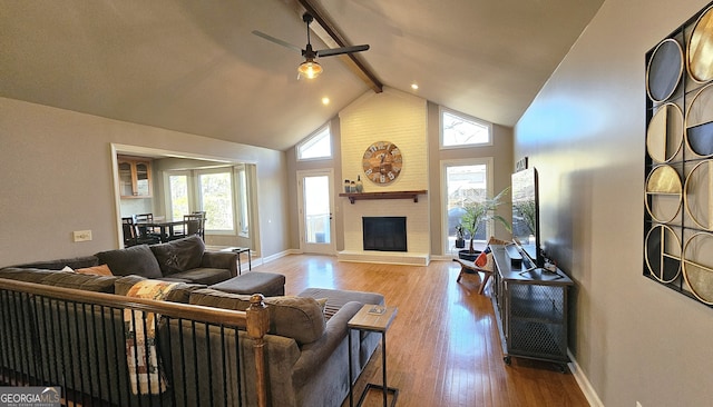 living room featuring beam ceiling, a wealth of natural light, a fireplace, and light hardwood / wood-style floors