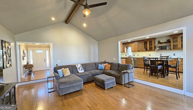 living room featuring sink, ceiling fan, beam ceiling, high vaulted ceiling, and light hardwood / wood-style floors