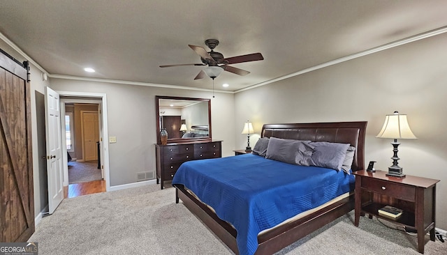 bedroom featuring ceiling fan, light colored carpet, ornamental molding, and a barn door