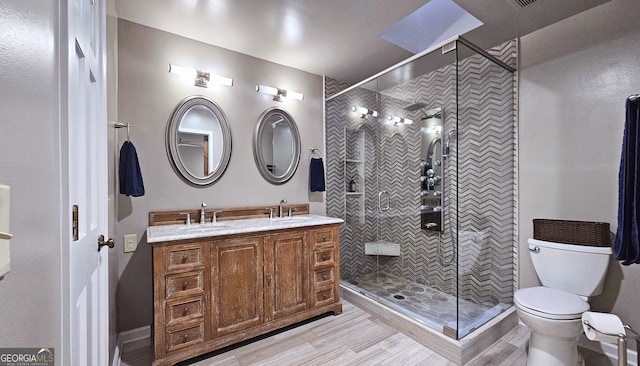 bathroom with vanity, tiled shower, and toilet