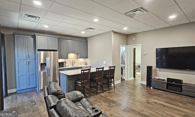 kitchen featuring stainless steel refrigerator with ice dispenser, dark hardwood / wood-style flooring, sink, and a breakfast bar