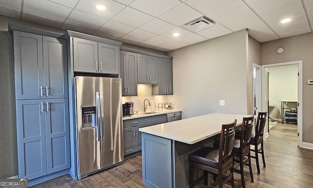 kitchen with a kitchen island, appliances with stainless steel finishes, dark hardwood / wood-style floors, sink, and a breakfast bar area