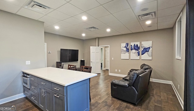 living room featuring a drop ceiling and dark wood-type flooring