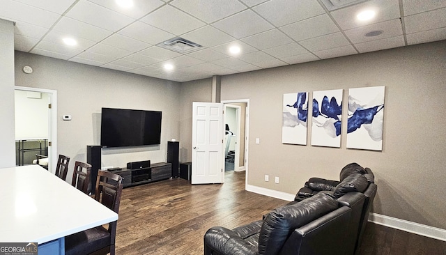 living room featuring a drop ceiling and dark hardwood / wood-style flooring