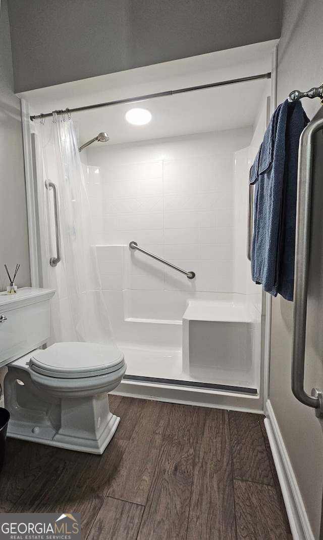 bathroom featuring wood-type flooring, toilet, and curtained shower