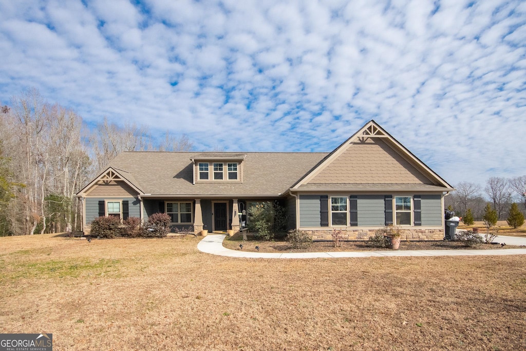 craftsman house featuring stone siding and a front yard