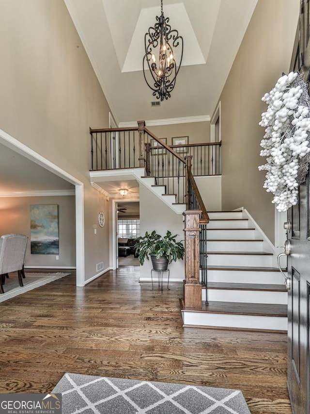 foyer with ornamental molding, a chandelier, a high ceiling, and dark hardwood / wood-style flooring