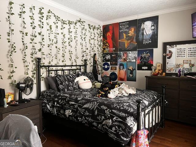 bedroom with crown molding, dark wood-type flooring, and a textured ceiling