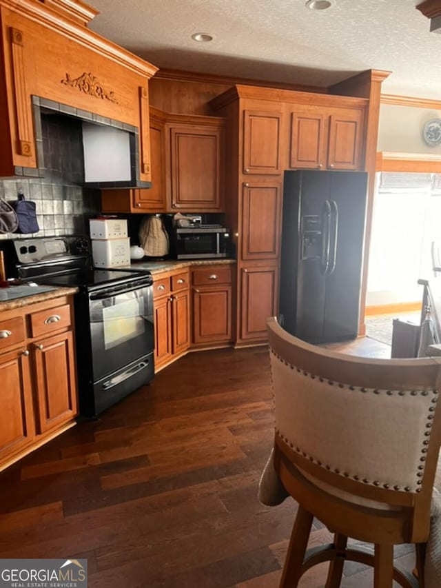 kitchen featuring dark hardwood / wood-style floors, decorative backsplash, ornamental molding, black appliances, and a textured ceiling