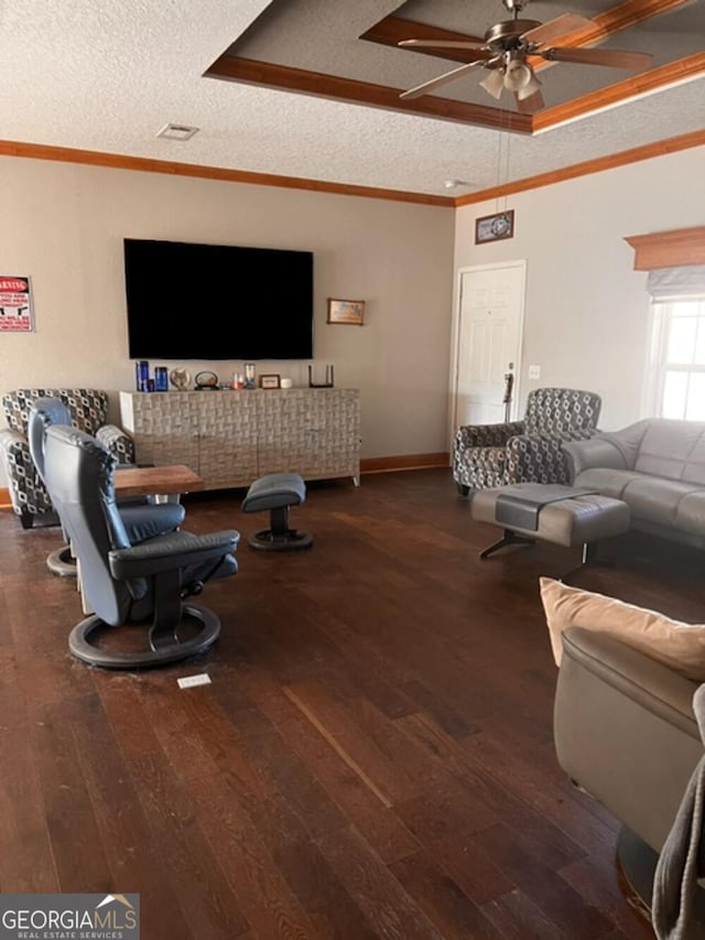 living room featuring ceiling fan, crown molding, dark wood-type flooring, and a textured ceiling