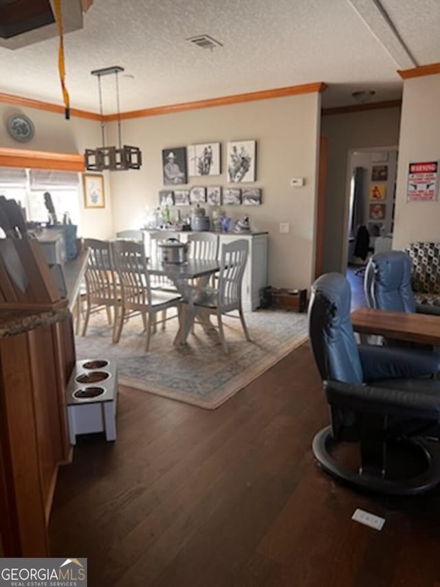 dining space featuring dark wood-type flooring, crown molding, and a textured ceiling