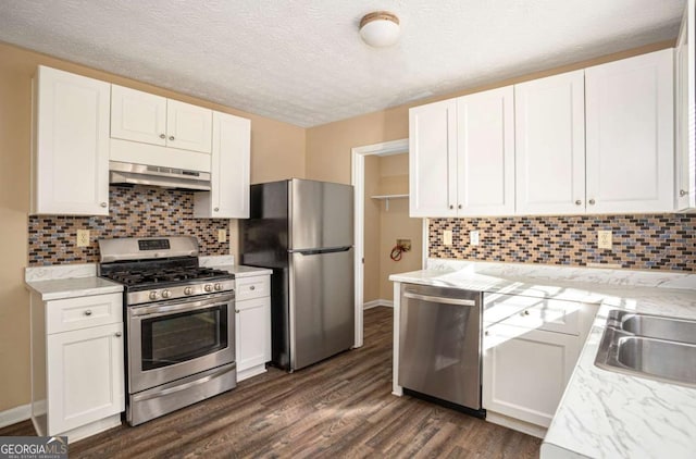 kitchen featuring white cabinetry, backsplash, stainless steel appliances, dark wood-type flooring, and a textured ceiling