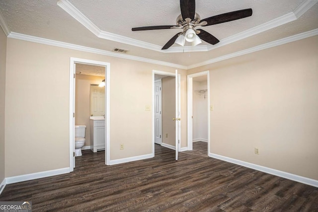 unfurnished bedroom with dark wood-type flooring, ensuite bathroom, ornamental molding, a tray ceiling, and ceiling fan