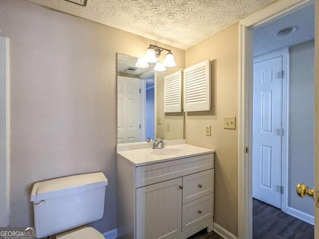 bathroom with toilet, a chandelier, a textured ceiling, vanity, and hardwood / wood-style flooring