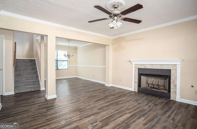 unfurnished living room with ceiling fan with notable chandelier, a tiled fireplace, ornamental molding, dark wood-type flooring, and a textured ceiling