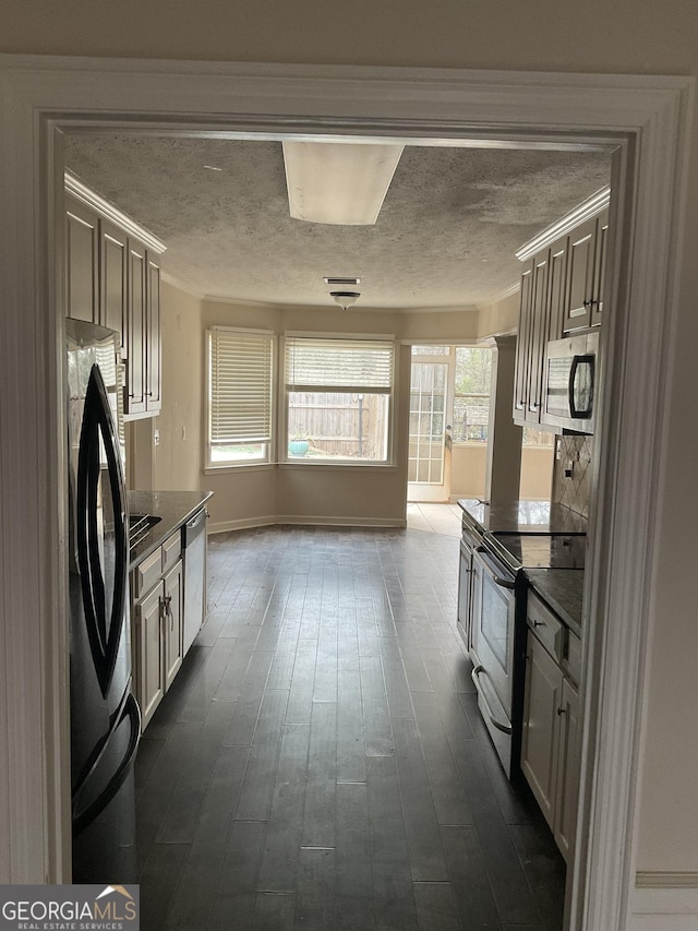 kitchen featuring stainless steel appliances, crown molding, a textured ceiling, and dark hardwood / wood-style flooring