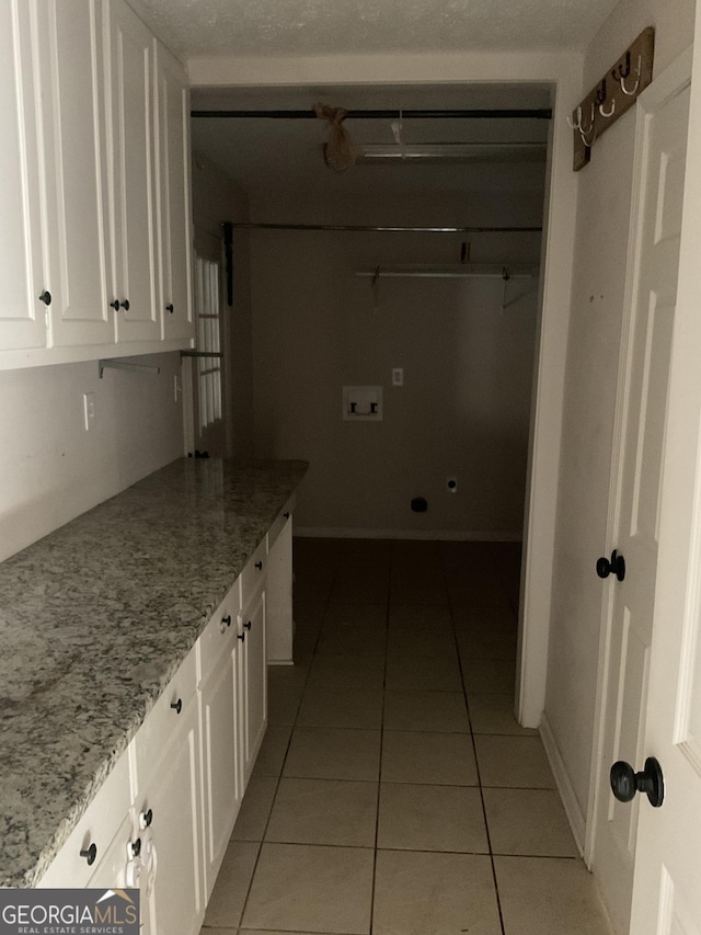 washroom featuring cabinets, light tile patterned flooring, and washer hookup