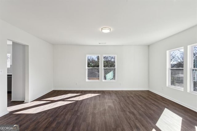 unfurnished room with plenty of natural light and dark hardwood / wood-style flooring