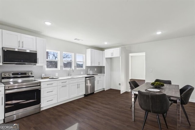 kitchen with white cabinetry, sink, backsplash, dark hardwood / wood-style flooring, and stainless steel appliances