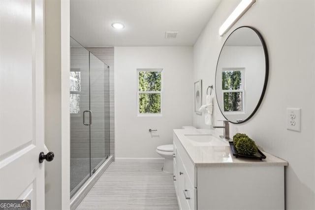 bathroom with walk in shower, vanity, and toilet