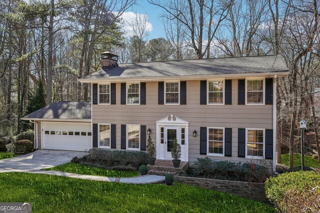 colonial house featuring a garage and a lawn