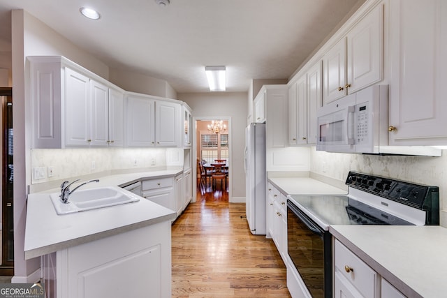 kitchen with white appliances, white cabinets, light hardwood / wood-style floors, sink, and a chandelier