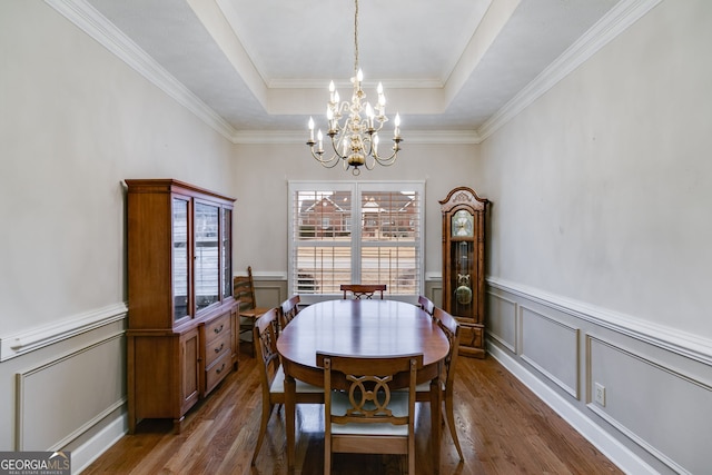 dining area featuring a tray ceiling, dark hardwood / wood-style floors, crown molding, and an inviting chandelier