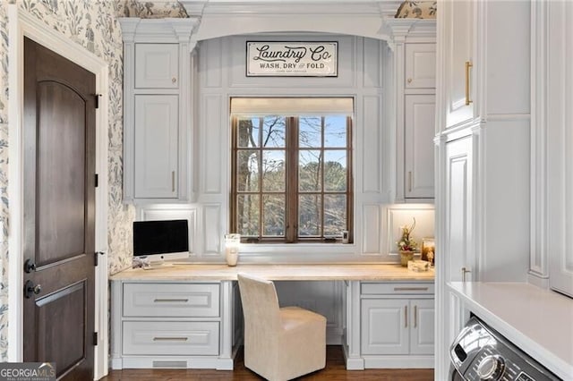 home office with crown molding, built in desk, and washer / dryer