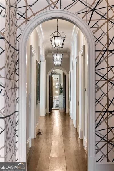 corridor featuring crown molding and a chandelier