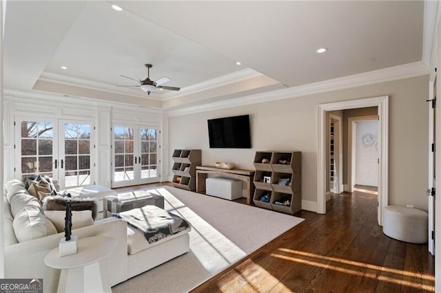 living room with french doors, ornamental molding, a raised ceiling, and dark wood-type flooring