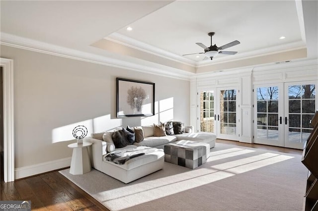 living room with dark hardwood / wood-style flooring, a tray ceiling, crown molding, and french doors